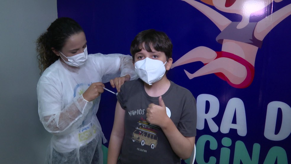 Breno Diniz, de 11 anos, foi com o pai tomar a vacina contra a Covid — Foto: Reprodução/TV Globo