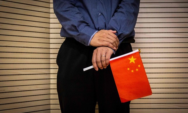 Com bandeira da China na mão, homem acompanha apresentação para comemorar o Dia Nacional da China, em Hong Kong
