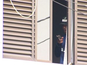 Criminoso apareceu diversas vezes na janela segurando uma arma (Foto: Reprodução / TV Tribuna)
