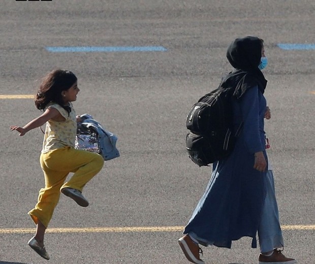 Menina afegã pula de alegria ao desembarcar na Bélgica (Foto: Reuters/BBC News)