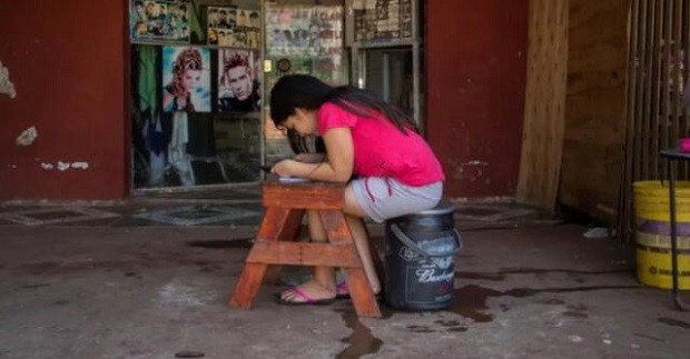 Criança estudando com o Wi-Fi de salão de cabeleireiro, no Paraguai (Foto: Reprodução)