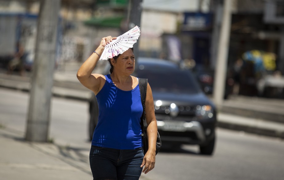 Mulher usa um leque para se proteger do sol na Avenida Vicente de Carvalho, no Rio de Janeiro. Foto de Márcia Foletto