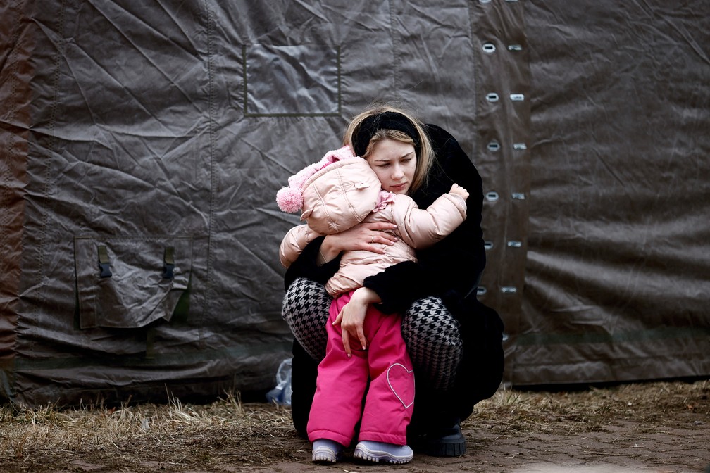 28 de fevereiro - Uma mulher que fugiu da invasão russa na Ucrânia abraça uma criança em um campo de refugiados temporário em Przemysl, na Polônia — Foto: Yara Nardi/Reuters