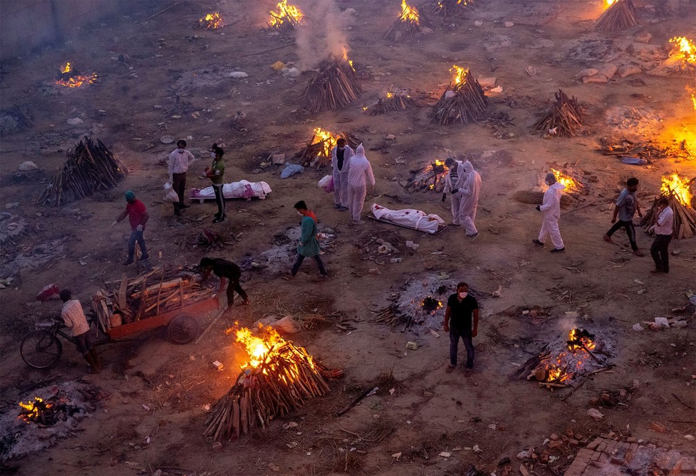 29 de abril - Parentes aguardam para cremar vítimas da Covid-19 entre piras funerárias de crematório nos arredores de Nova Délhi, na Índia. Cremações em massa começaram a ser feitas devido à disparada no número de mortes pelo país — Foto: Danish Siddiqui/Reuters
