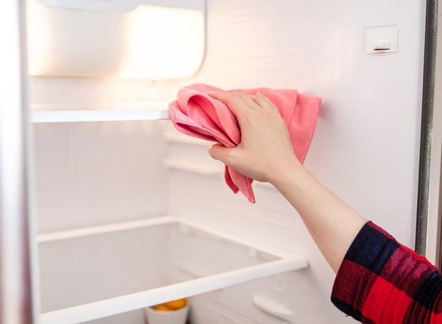 Limpe a parte interna da geladeira com um pano umedecido com solução de água sanitária e seque bem com outro pano (Foto: Getty Images)