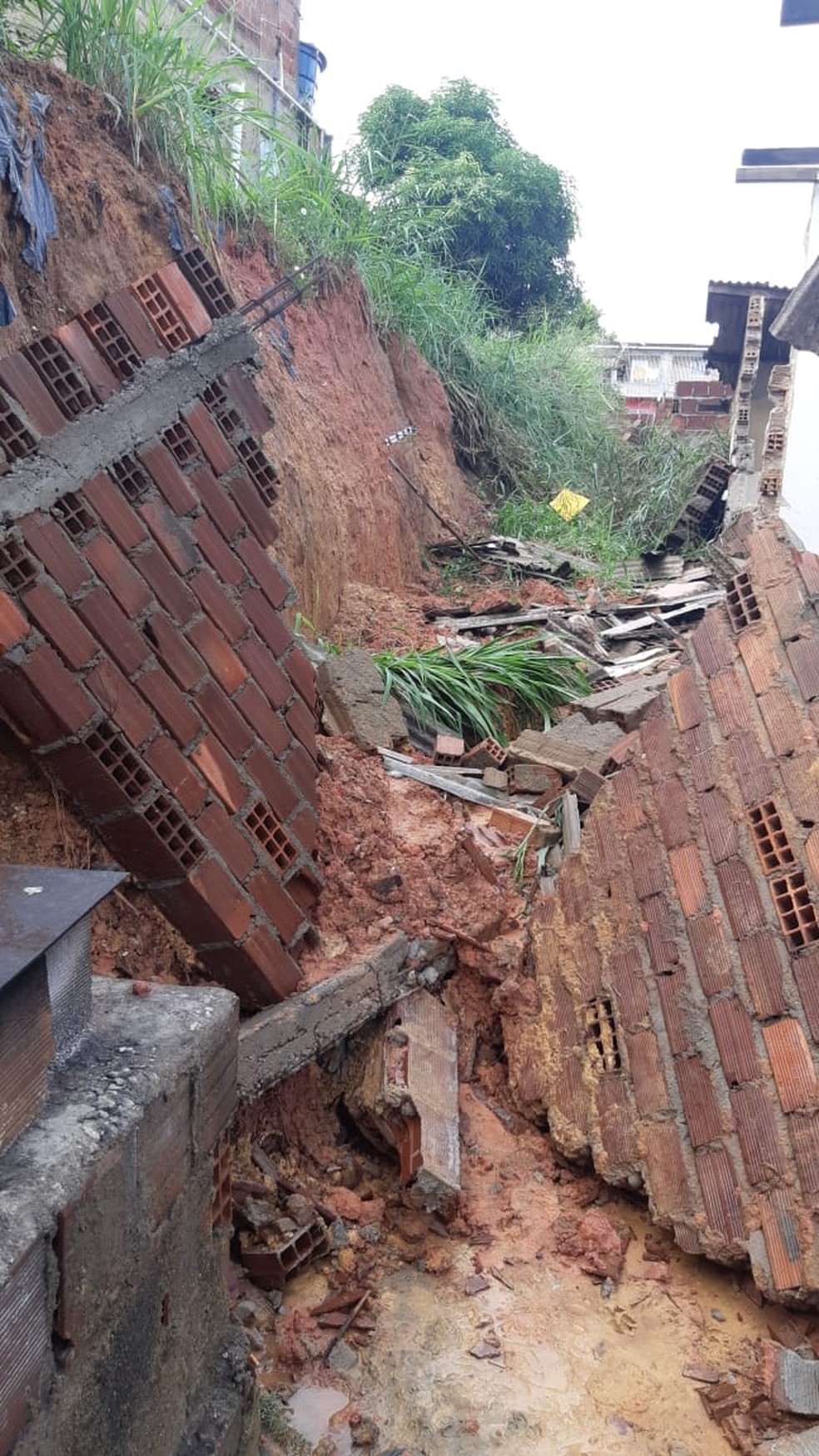 A Defesa Civil do município informou que o encharcamento da encosta provocou a queda do muro — Foto: Reprodução/WhatsApp