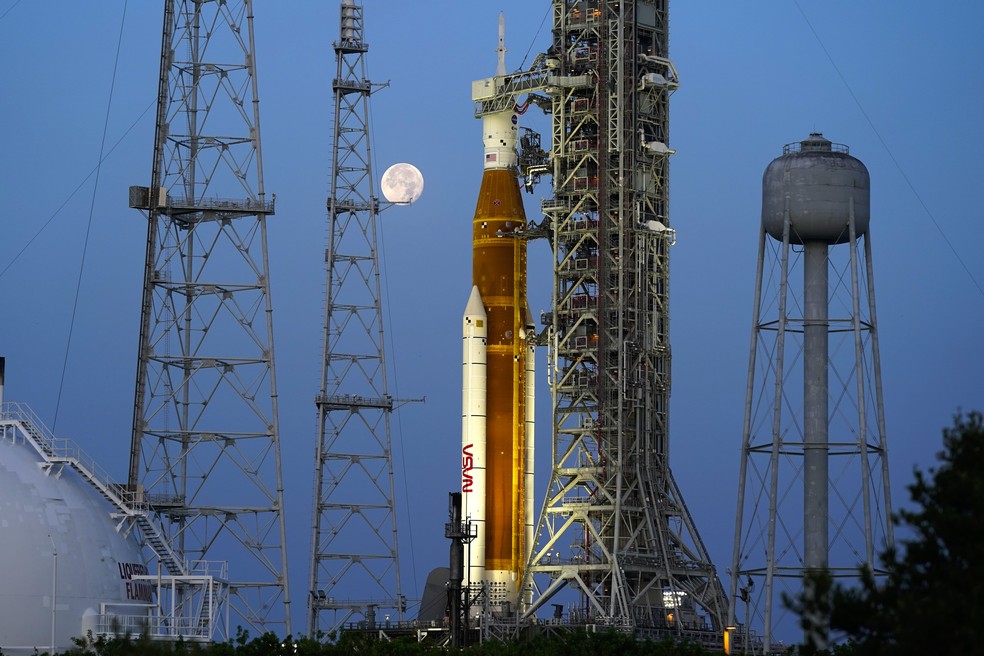 A Lua se põe em frente ao foguete Artemis da Nasa, com a espaçonave Orion a bordo, no bloco 39B do Centro Espacial Kennedy, em 15 de junho de 2022. — Foto: AP Photo/John Raoux
