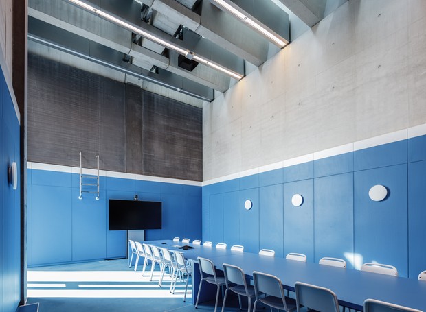 Entre os espaços está uma reuniões que parece ficar no fundo de uma piscina azul brilhante (Foto: Reprodução/Dezeen)
