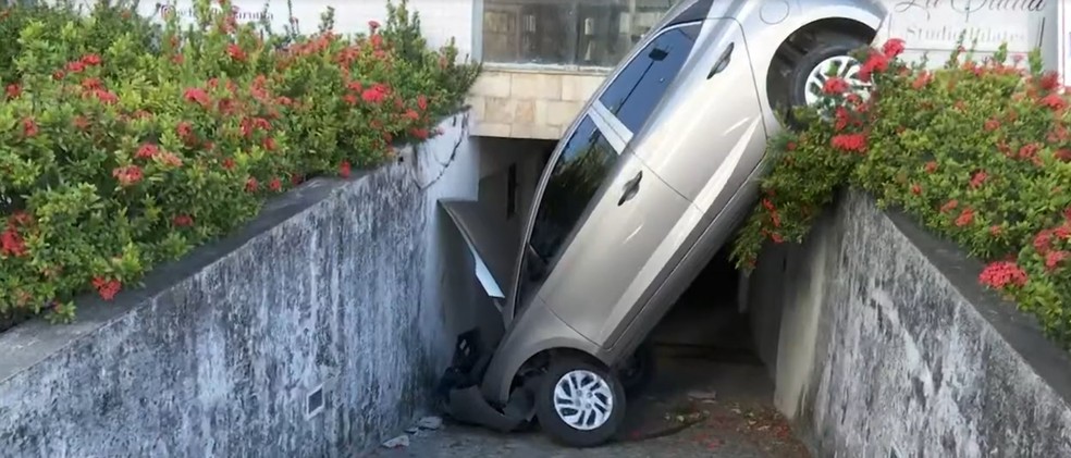 Motorista perde controle de carro, bate em poste e cai na entrada de garagem de prédio em João Pessoa