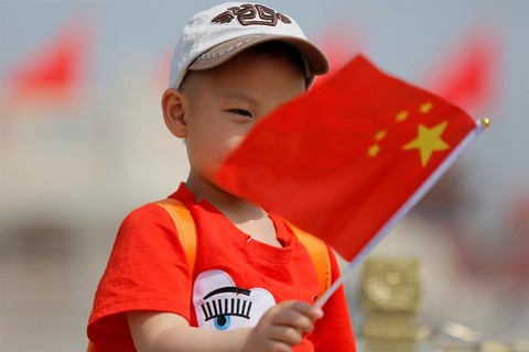 Criança segura bandeira da China, na Praça da Paz Celestial, no dia 1º de maio. Muitas pessoas aproveitaram os três dias de feriado no país para visitar locais turísticos