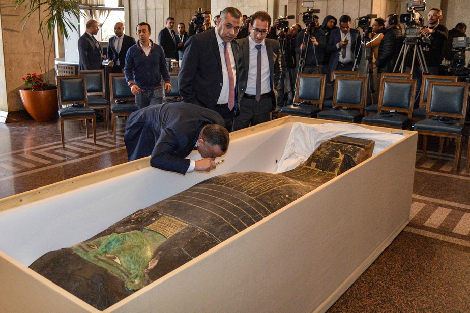 Mostafa Waziri, do Conselho de Antiguidades do Egito, usa uma lupa para inspecionar sarcófago de madeira que retornou ao país