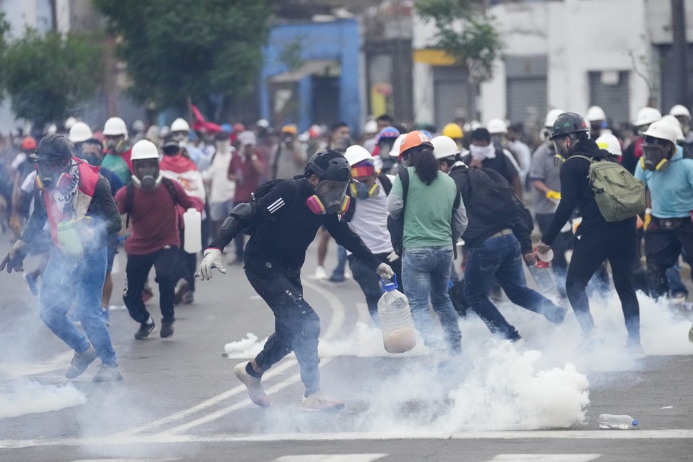 Manifestantes anti-governo pegam bombas de gás lacrimogêneo jogadas contra eles em Lima, Peru, em 28 de janeiro de 2023 — Foto: Guadalupe Pardo/AP