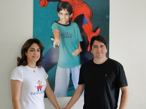 Carla e o marido, Marcelo Karam, diante de uma foto do filho.  (Foto: Thaís Leocádio/G1)