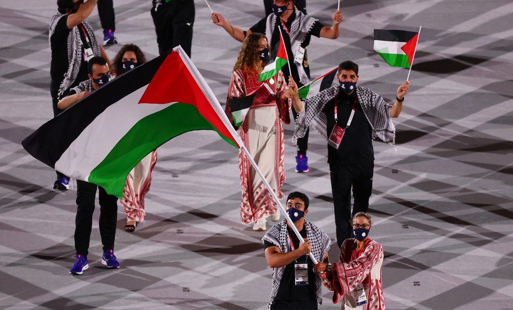 Dania Nour e Mohammed Hamada levam a bandeira da Palestina durante a cerimônia de abertura dos Jogos Olímpicos de Tóquio, no Japão — Foto: Mike Blake/Reuters
