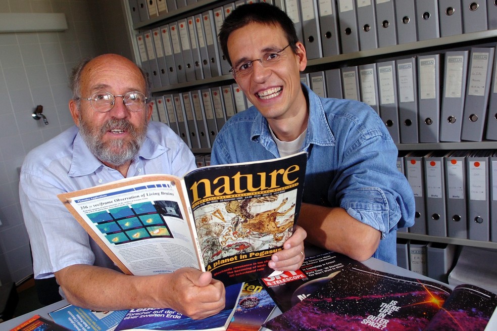 Na foto, de 2005, Michel Mayor e Didier Queloz posam com um exemplar da revista científica 'Nature' sobre a descoberta do exoplaneta — Foto: Laurent Gillieron, Keystone via AP