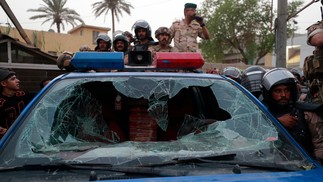 Carro da policia iraquiana é atingido durante confrontos entre manifestantes e a tropa de choque, em frente ao escritório de emissão de visto turco em Bagdá. A revolta é reação a um bombardeio que matou civis em território curdo no norte do país  — Foto: AHMAD AL-RUBAYE / AFP