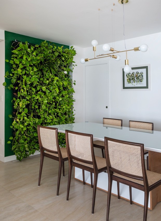 Sala de jantar. O jardim vertical recebeu uma moldura verde e fica na entrada do apartamento. Na parede, quadro do artista Carlos Páez Vilaró (Foto: Julia Ribeiro / Divulgação)