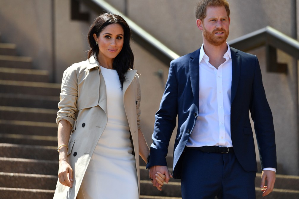 Príncipe Harry e Meghan Markle descem escada da Ópera de Sydney, na Austrália, nesta terça-feira (16)  — Foto: Saeed Khan / AFP