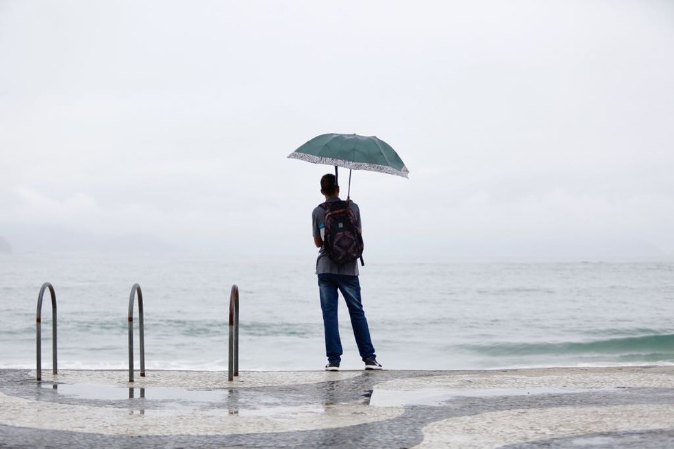 De guarda-chuva, homem observa o mar de Copacabana em 2018 — Foto: Marcos Serra Lima/G1