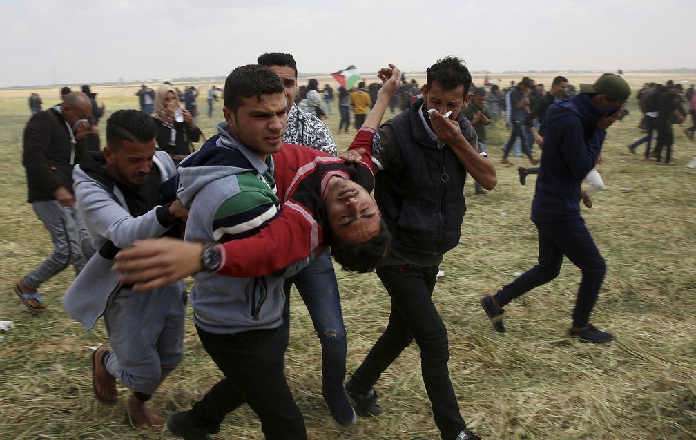 Palestino ferido é carregado nesta sexta-feira (30) durante confronto na Faixa de Gaza (Foto: AP Photo/Adel Hana)