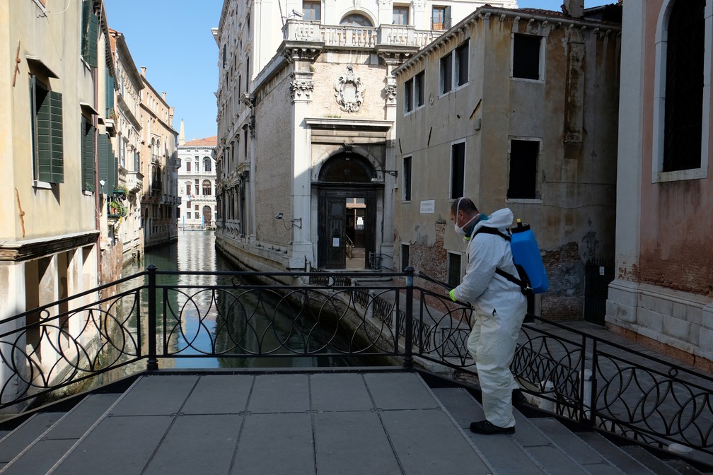 Homem com aparato de segurança limpa ponte em Veneza, na Itália, nesta quinta-feira (16) — Foto: Manuel Silvestri/Reuters