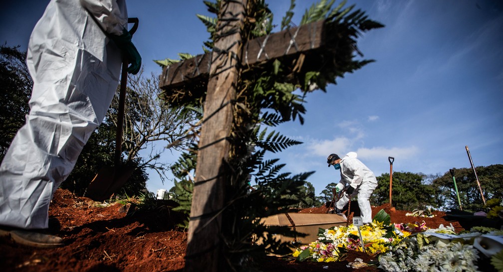 Funcion&aacute;rios vestindo roupas de prote&ccedil;&atilde;o contra o coronav&iacute;rus sepultam os corpos de v&iacute;timas da Covid-19 no Cemit&eacute;rio da Vila Formosa, na Zona Leste de S&atilde;o Paulo,. &mdash; Foto: Werther Santana/Estad&atilde;o Conte&uacute;do 