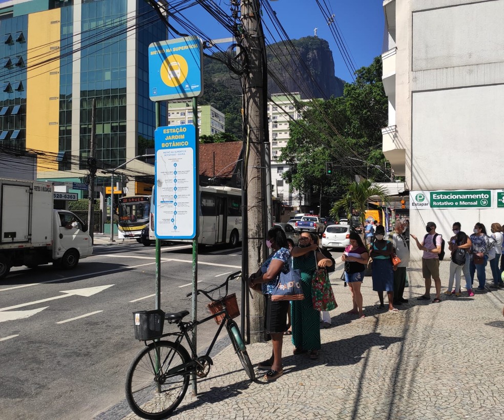 À espera do ônibus no Jardim Botânico, passageiros usaram sombra do poste para se proteger do sol no primeiro dia do verão — Foto: José Raphael Berrêdo/g1