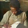 Foto: (Carolina Maria de Jesus autografando 'Quarto de despejo' em 1960 - foto colorida / Reprodução)