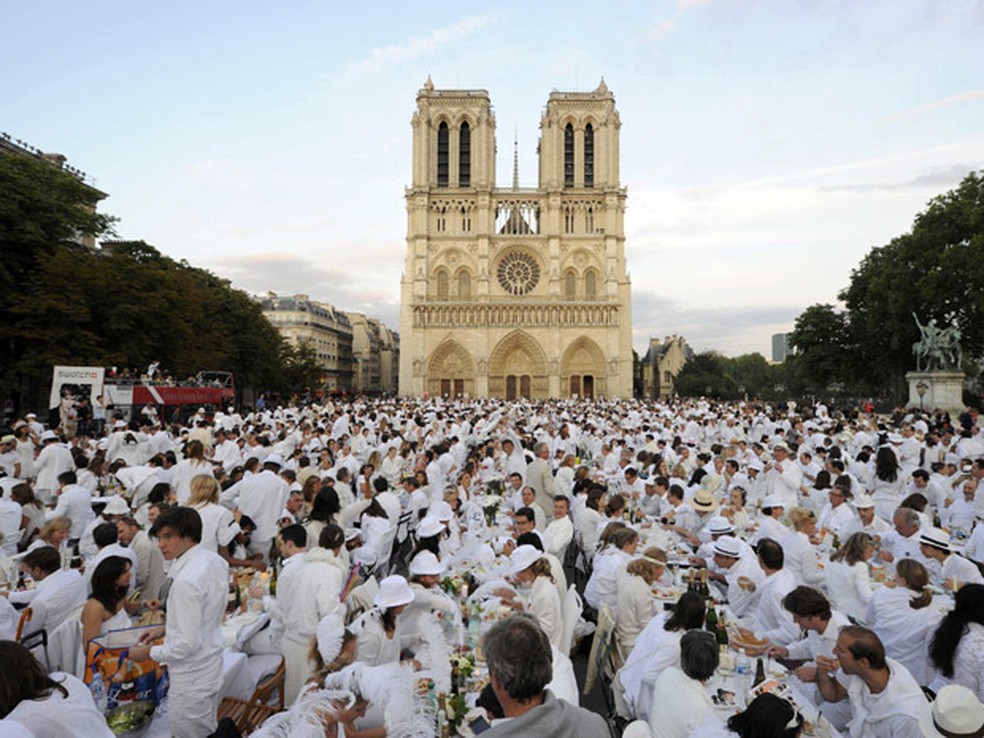 Comensais servem-se no tradicional 'Jantar Branco', em frente à Catedral de Notre Dame, em Paris, nesta quinta-feira (16) — Foto: Reuters