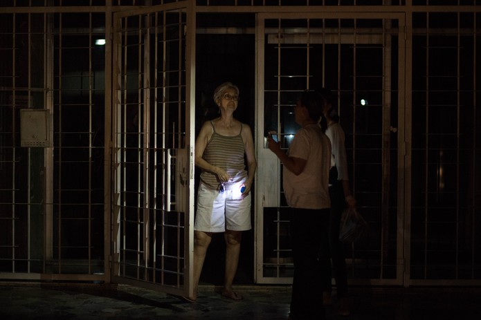 Mulher segura lanterna na porta de prédio residencial durante apagão em Caracas, Venezuela — Foto: Cristian Hernandez/AFP