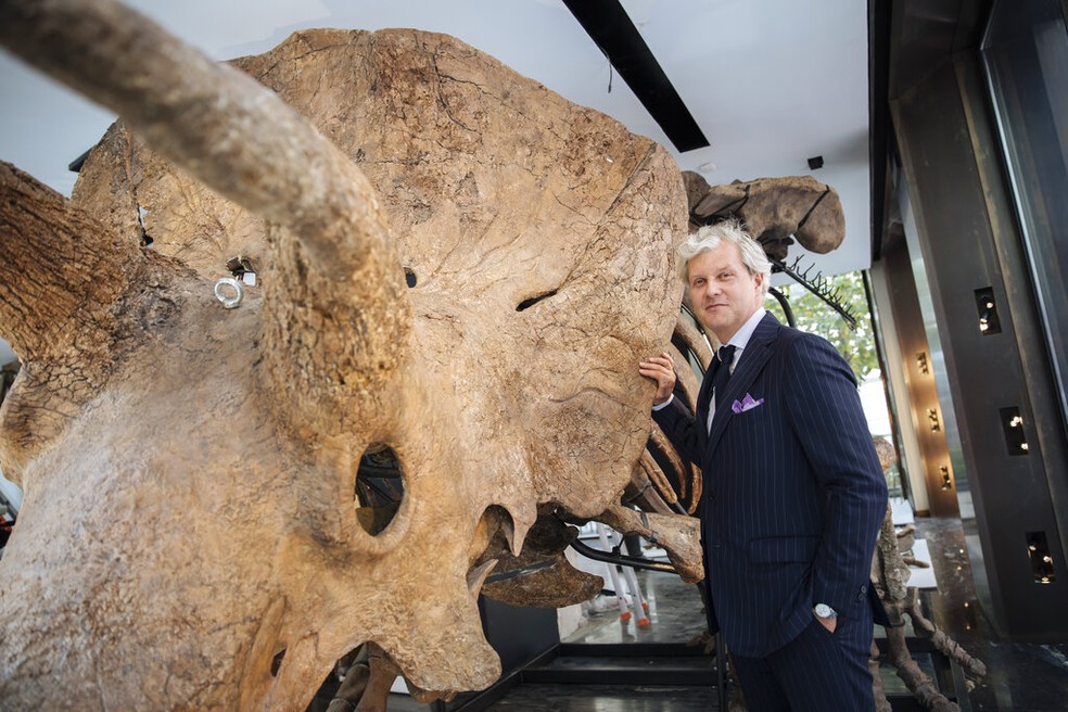 “Big John", o maior triceratops conhecido até hoje, acompanhado do leiloeiro Alexandre Giquello. — Foto: Lewis Joly/AP