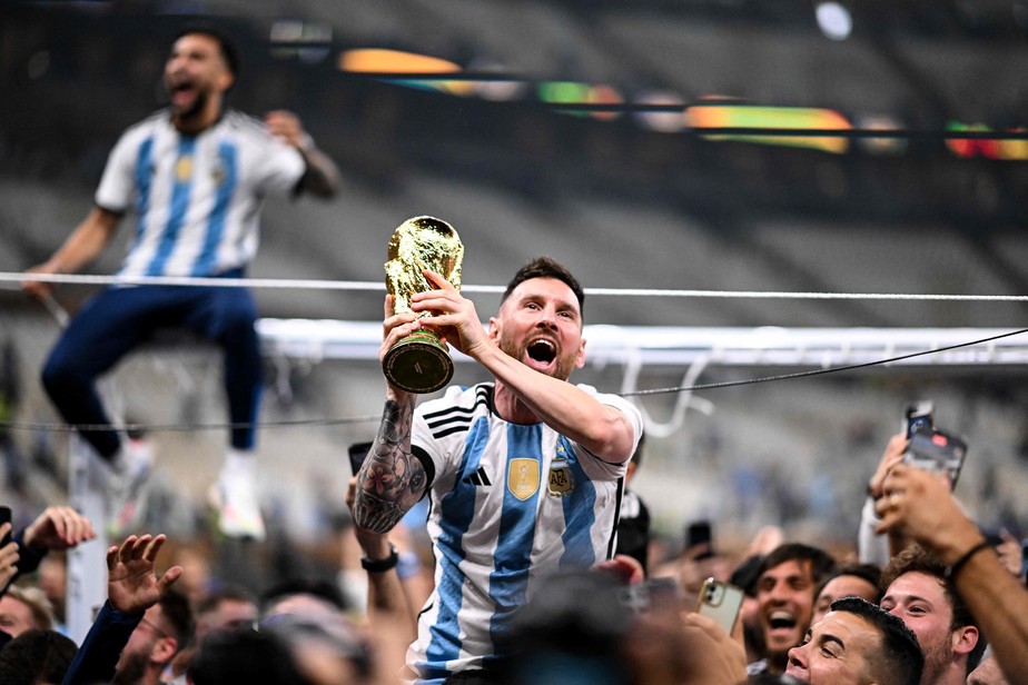 Lionel Messi carrega a taça e é carregado pela torcida argentina no Catar: herói nacional