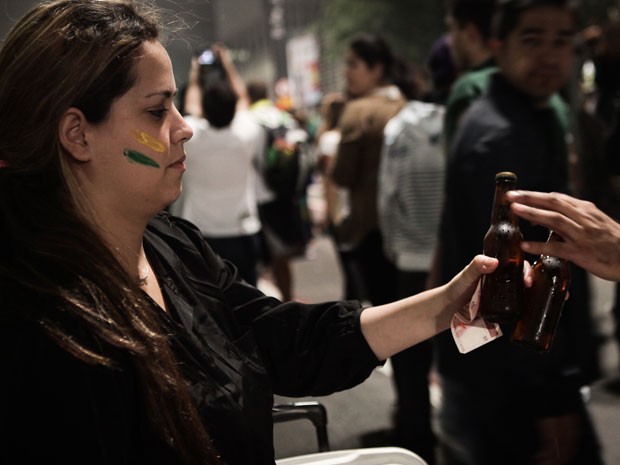 A vendedora ambulante Aline Correia, 28, recebe dinheiro de cliente que comprou cerveja no protesto desta quinta-feira (21) na Avenida Paulista (Foto: Caio Kenji/G1)