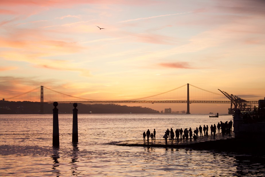 Grupo de pessoas assiste ao pôr do sol no Cais das Colunas, em Lisboa