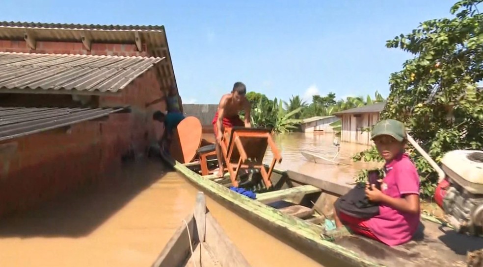 Morador tirar coisas de dentro de casa após ela ter sido invadida  — Foto: Reprodução/ Rede Amazônica Acre