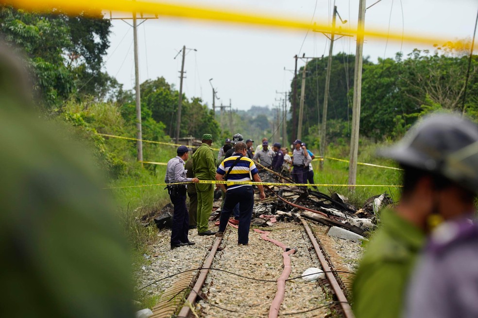Equipe de resgate e busca trabalha entre destroços de avião que pararam sobre trilhos de uma rodovia após acidente aéreo em Havana (Foto: Ramon Espinosa/AP)
