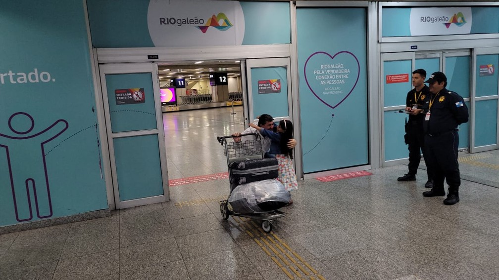 Rodolpho Valério Leitão Maia, preparador físico, abraça a filha ao chegar no Galeão — Foto: Cristina Boeckel / g1