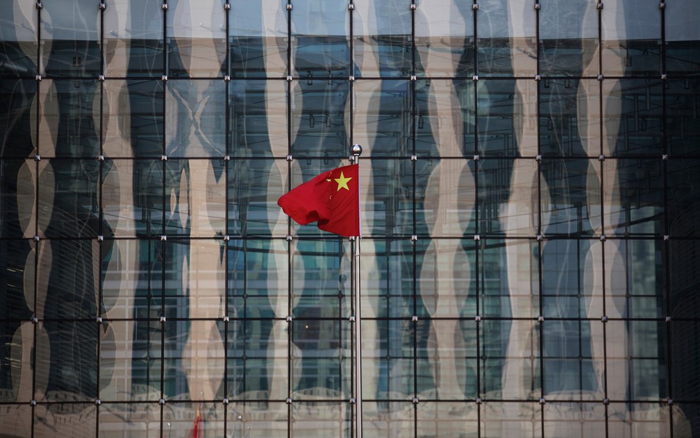 A bandeira da China é vista na sede de um banco no centro de Pequim. O banco central do país está pronto para cortar as taxas de juros novamente, preocupado que a queda dos preços possa desencadear uma onda de calotes de dívidas, falências de empresas e d — Foto: Kim Kyung-Hoon/Reuters