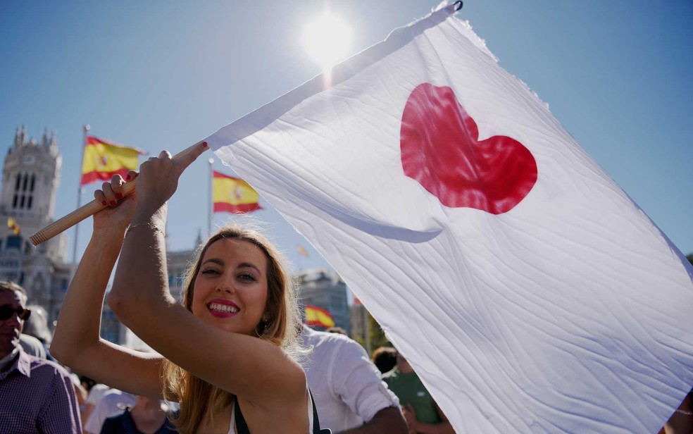 Mulher segura bandeira branca com coração durante manifestação em Madri, neste sábado (7) (Foto: Gabriel Bouys/AFP)