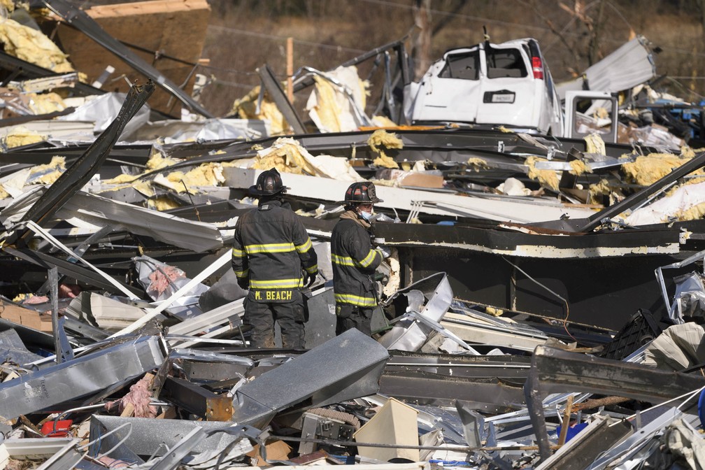 Em Mayfield, integrantes de equipe de emergência vasculham escombros da fábrica de velas em Mayfield, na qual mais de cem pessoas trabalhavam quando o tornado passou. Dezenas morreram e muitos ainda estão desaparecidos.  — Foto: John Amis/AFP