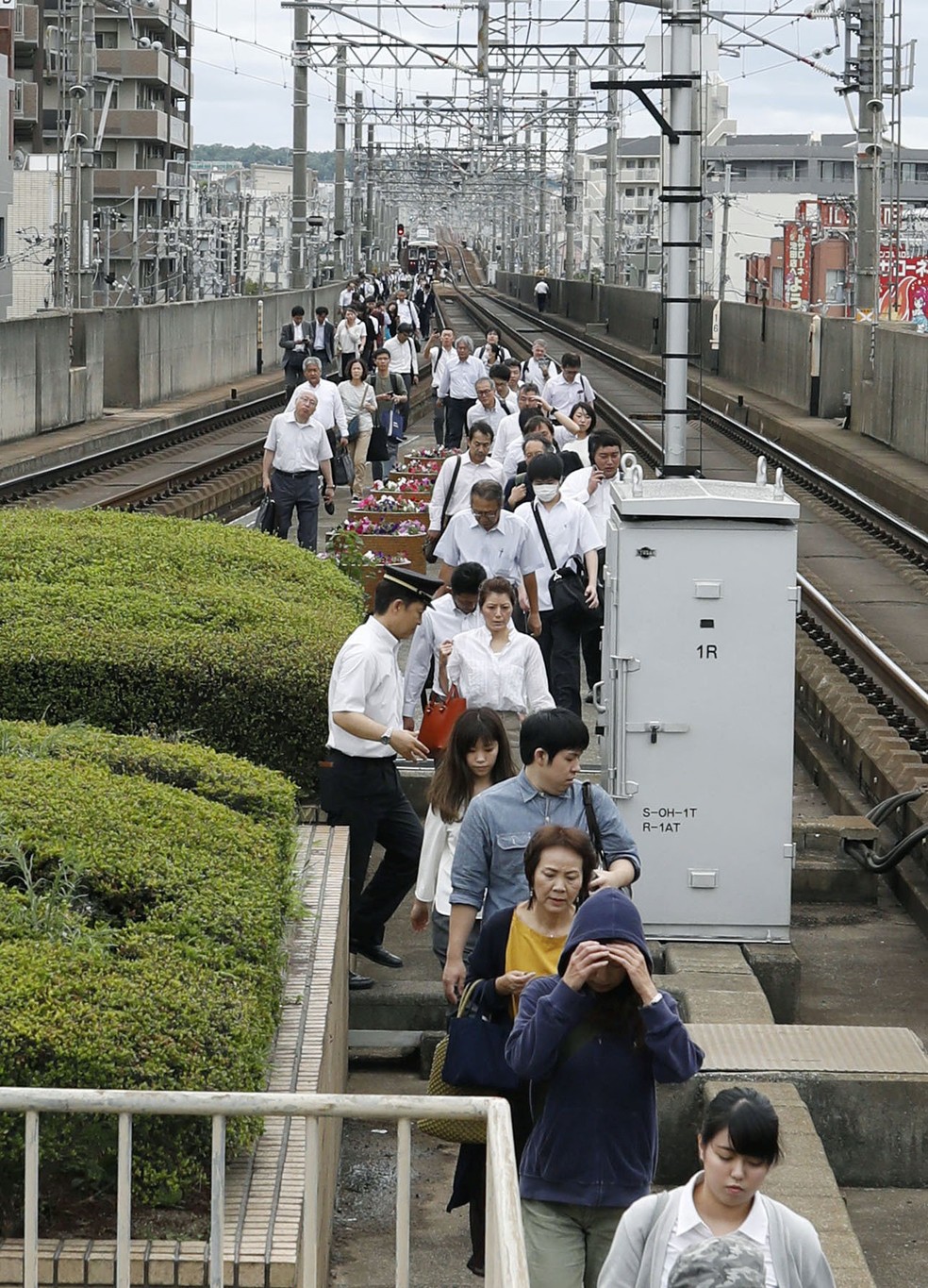 Passageiros andam pelos trilhos após trem parar em Osaka (Foto: Kyodo/via Reuters)