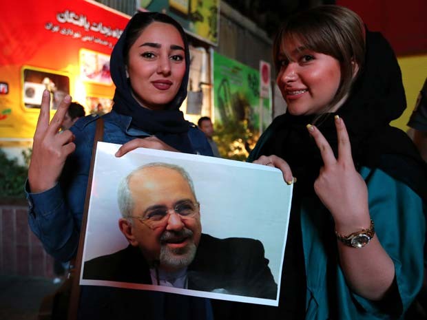Mulheres seguram foto do ministro das Relações Exteriores do Irã, Javad Zarif, ao comemorar o acordo anunciado nesta terça-feira (14) (Foto: AFP PHOTO / ATTA KENARE)
