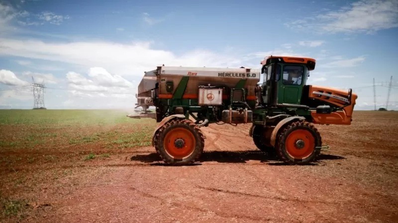 Trator carrega fertilizante para plantação de soja perto de Brasília (Foto: Reuters via BBC)
