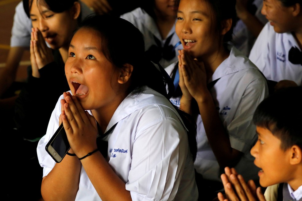 Colegas de escola de alguns dos meninos presos em caverna na Tailândia comemoram anúncio de mais um resgate nesta segunda-feira (9)  (Foto: Tyrone Siu/ Reuters)