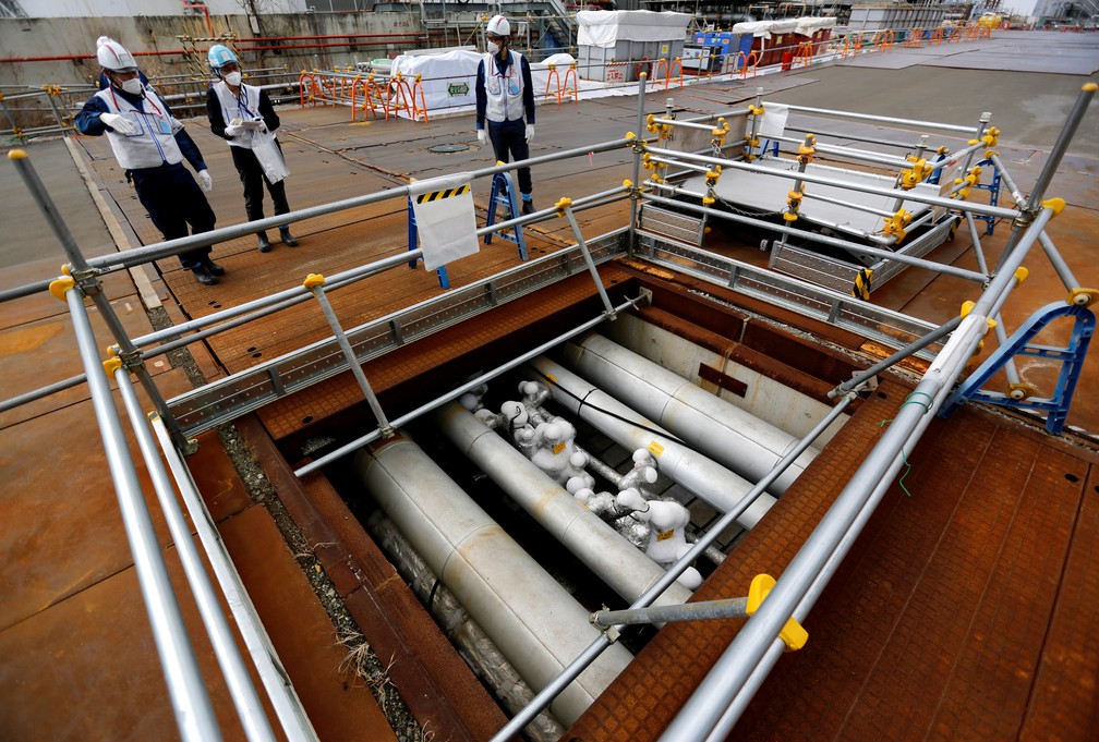 Trabalhadores da Tepco observam barreira para impedir vazamento de água contaminada na usina de Fukushima, no Japão — Foto: Issei Kato/Reuters