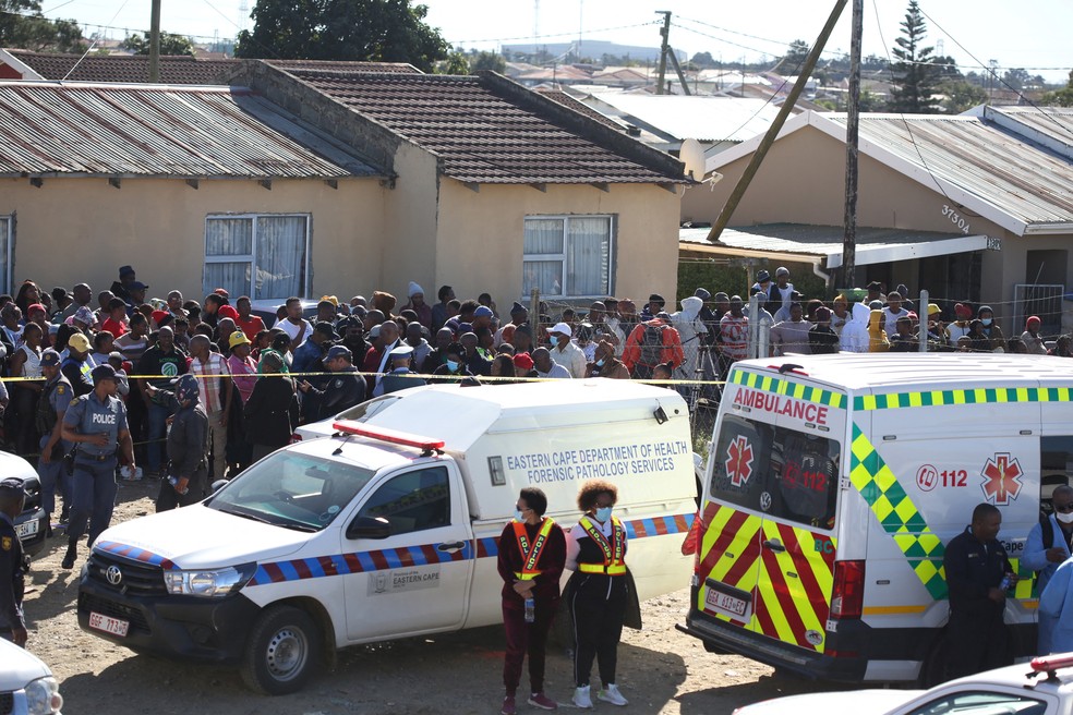 Multidão acompanha retirada de ao menos 22 corpos de jovens encontrados dentro de bar em East London, na África do Sul, em 26 de junho de 2022. — Foto: Reuters
