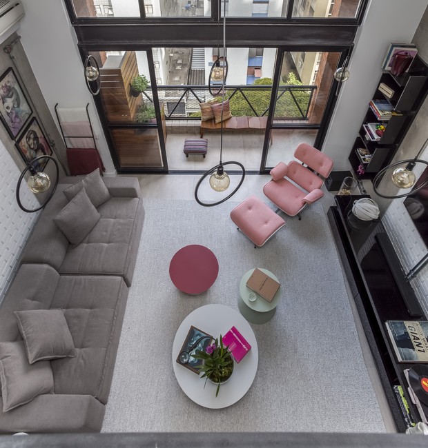 Apesar do pé-direito alto, a sala de estar tem mood acolhedor graças às escolhas dos elementos que a compõem, como sofá, mesinhas e tapete. Projeto do escritório Korman Arquitetos (Foto: Divulgação)