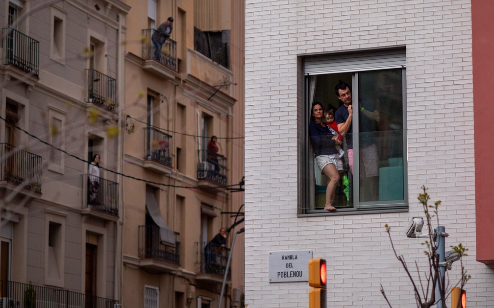 Uma família é vista na janela de sua casa durante um isolamento nacional para combater o novo coronavírus em Barcelona, na ​​Espanha, em 29 de março — Foto: Emilio Morenatti/AP