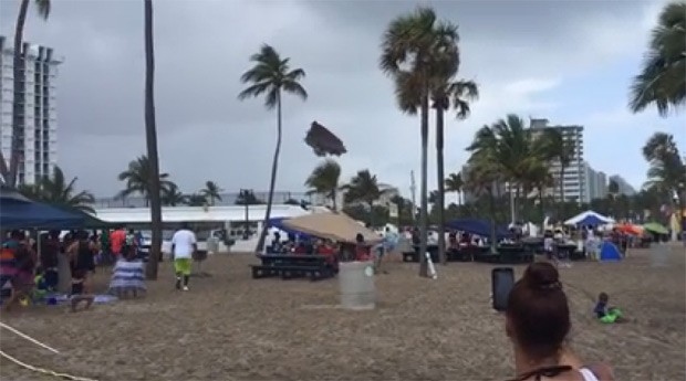 Banhistas em praia de Fort Laderdale, nos EUA, observam e filmam brinquedo, que voou por sobre coqueiros levado por ventania (Foto: Reprodução / Facebook)