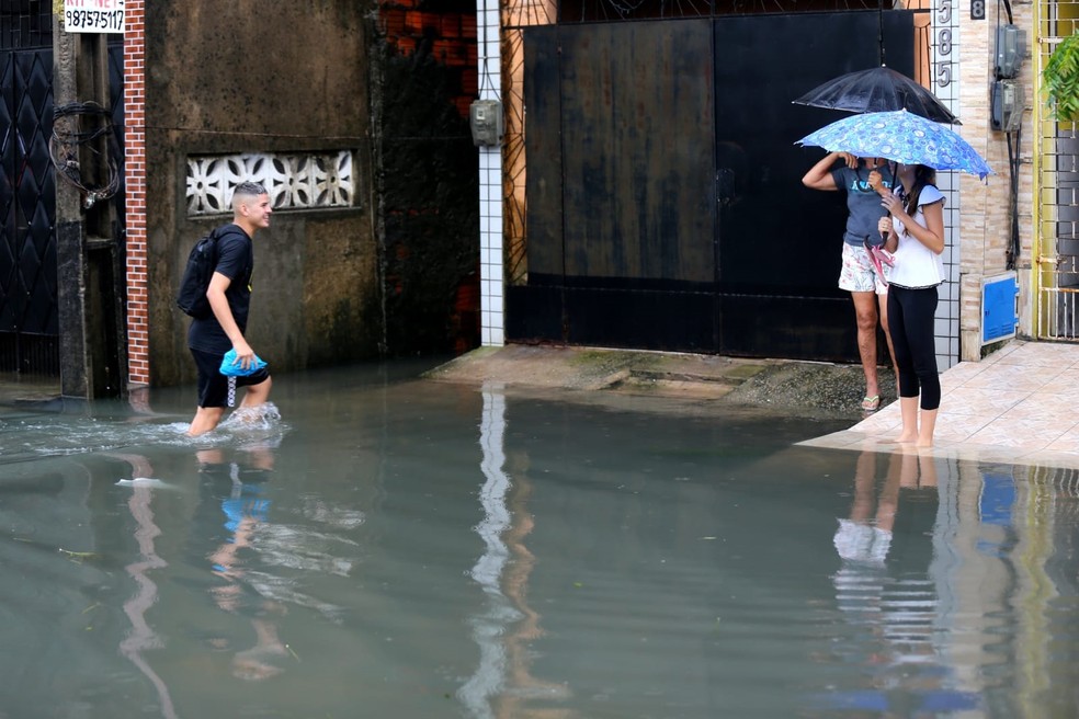 Moradores da periferia de Fortaleza andam em água enlameada em dia de chuva — Foto: Fabiane de Paula/SVM